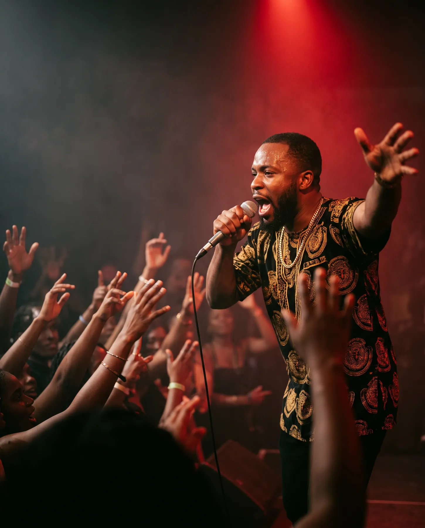 A hypeman on stage with the microphone raised, commanding an excited crowd